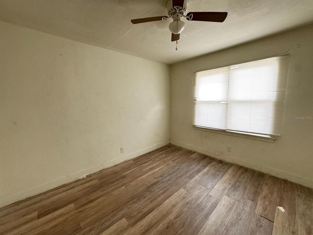 A bedroom features light-colored walls, a ceiling fan, a window with blinds, and wood-look flooring — 930 18TH STREET UNIT A, ORLANDO, FL