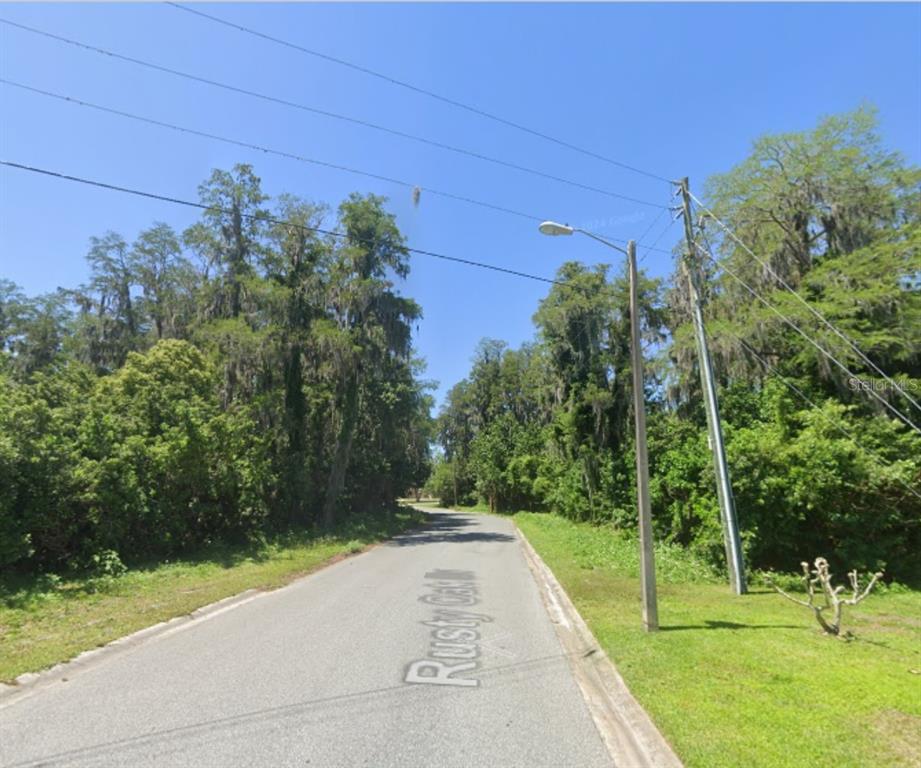 A paved road winds through a wooded area with overhead power lines and a street lamp — TBD BROKEN ARROW DRIVE, NEW PORT RICHEY, FL