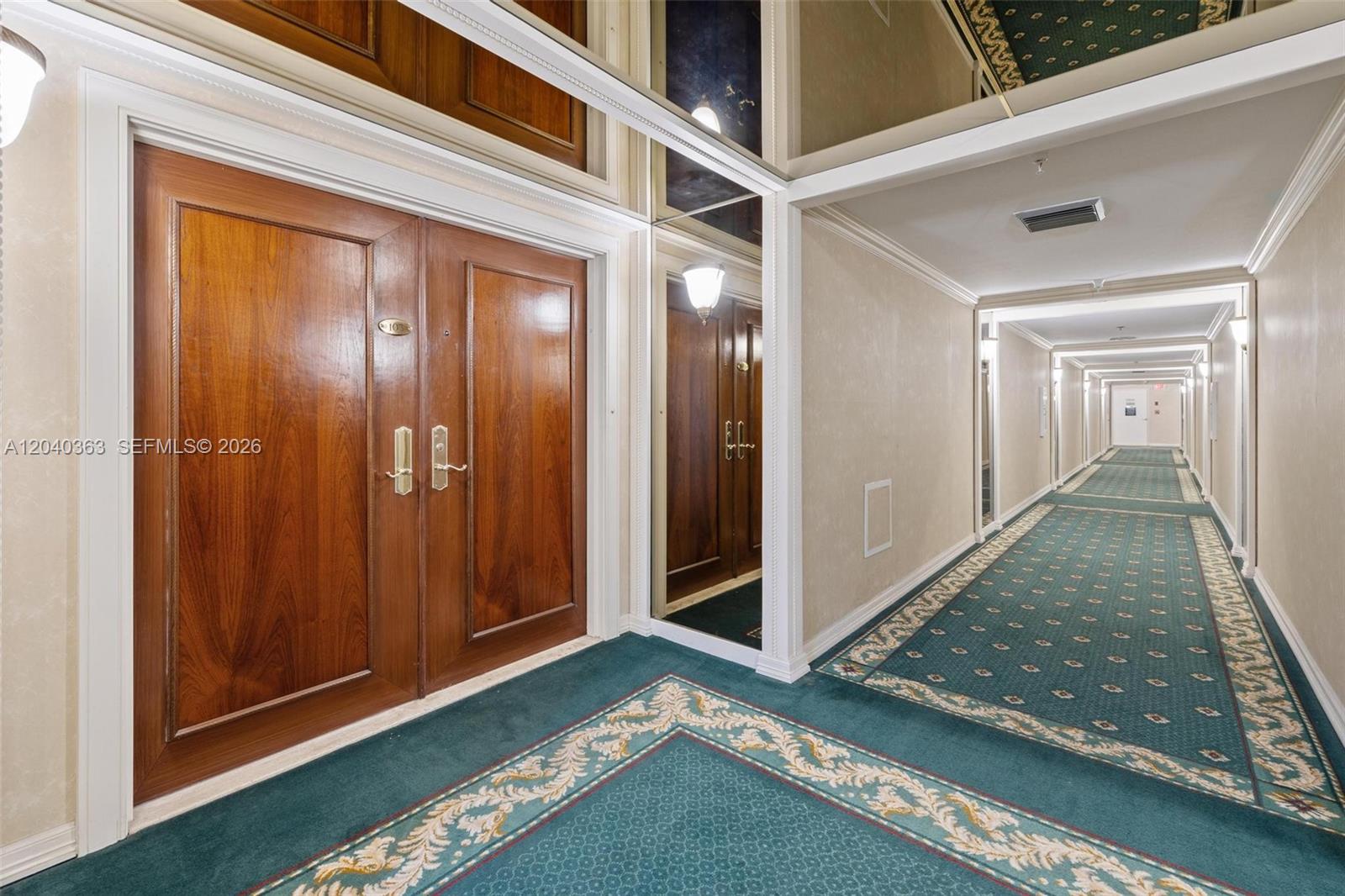 A hallway features green patterned carpeting, wooden double doors, and mirrored wall panels — 10175 Collins Ave # 103, Bal Harbour FL 33154, BAL HARBOUR, FL