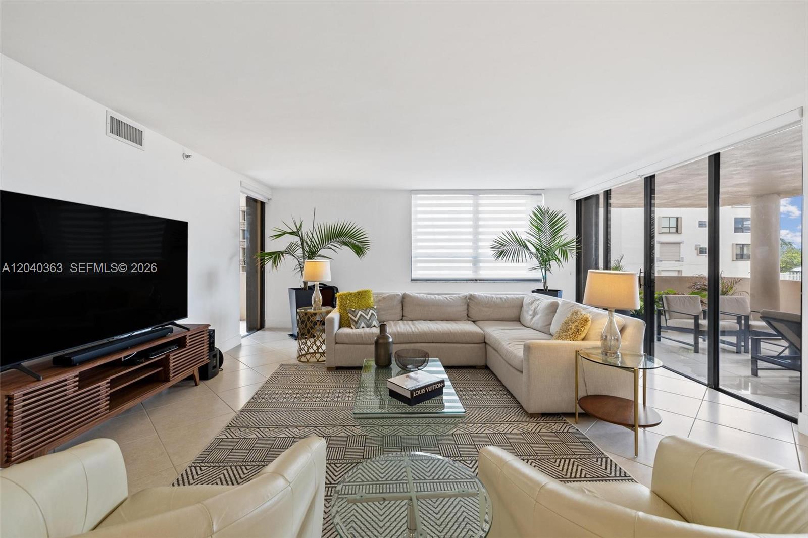 A living room features a sectional sofa, a glass coffee table, and a large balcony — 10175 Collins Ave # 103, Bal Harbour FL 33154, BAL HARBOUR, FL
