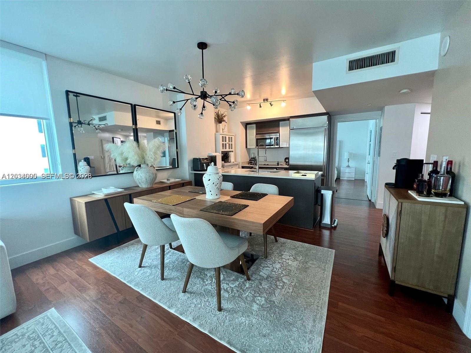 A dining area with a wooden table and chairs sits adjacent to an open kitchen — 500 Brickell Ave # 1410, Miami FL 33131, MIAMI, FL