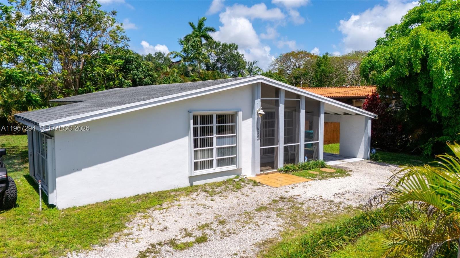 A white, single-story house with a gravel driveway and a screened-in front porch — 11600 NE 6th Ave, Biscayne Park FL 33161, BISCAYNE PARK, FL