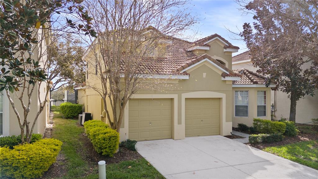 A two-story house with a two-car garage, beige stucco exterior, and a tiled roof — 2615 PAWNALL STREET, KISSIMMEE, FL
