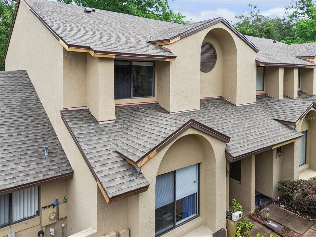 A two-story tan stucco townhouse features a covered carport and a landscaped front yard — 476 CLUB DRIVE, WINTER SPRINGS, FL