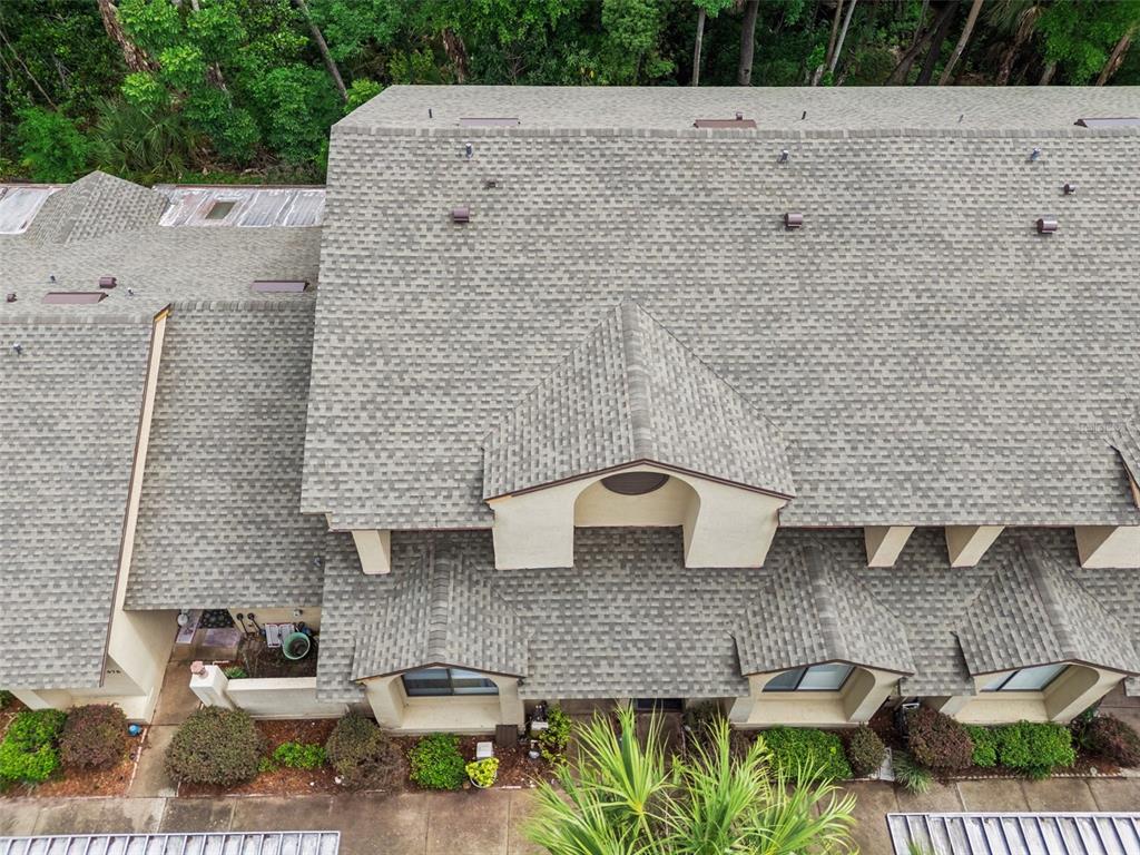An exterior view of a multi-story tan stucco townhouse with a shingled roof — 476 CLUB DRIVE, WINTER SPRINGS, FL