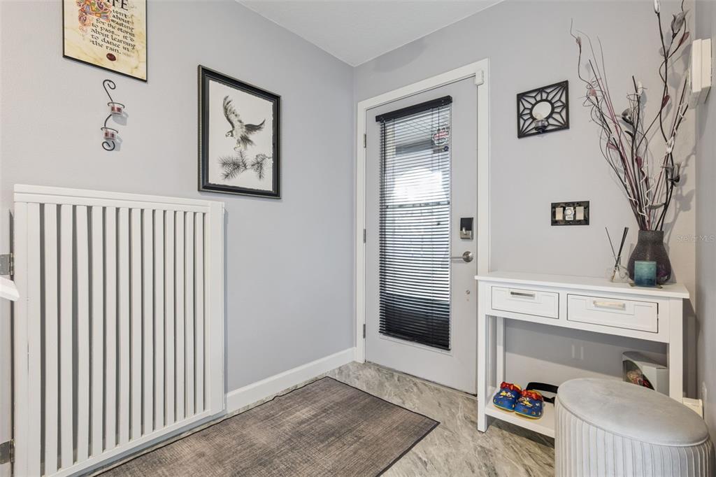 An entryway features a white console table, a radiator cover, and a door with blinds — 476 CLUB DRIVE, WINTER SPRINGS, FL