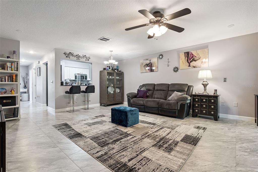 A living room features gray tile floors, a dark sofa, and a breakfast bar area — 476 CLUB DRIVE, WINTER SPRINGS, FL