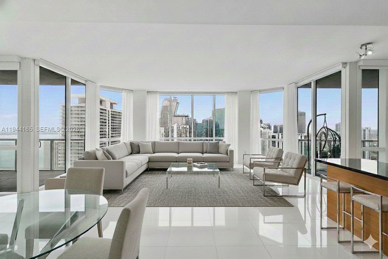 A modern living room features a large sectional sofa, glass coffee table, and floor-to-ceiling windows — 253 NE 2nd St # 4608, Miami FL 33132, MIAMI, FL