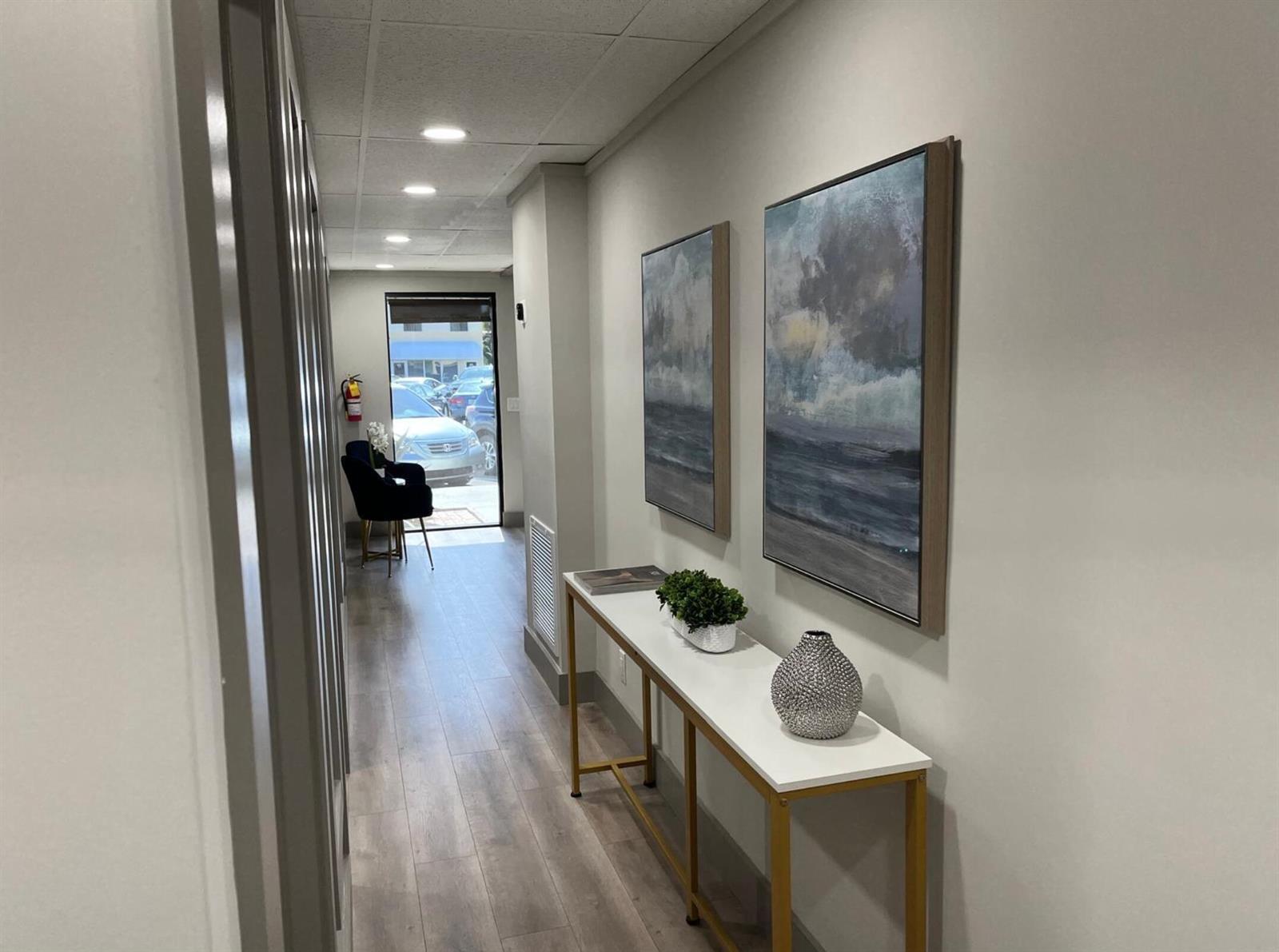 A hallway features a white console table, two framed landscape paintings, and a glass door — 828 SE 8th Avenue, Deerfield Beach FL 33441, DEERFIELD BEACH, FL