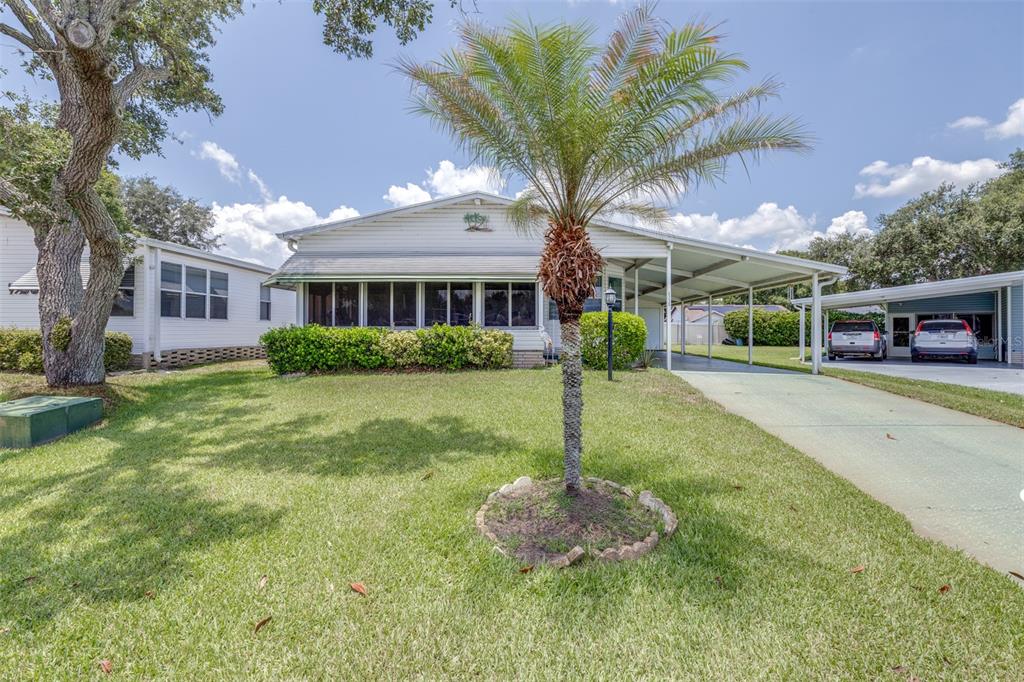 A single-story house with a screened front porch, a palm tree, and a carport — 6235 KNOTTY PINE DRIVE SE, WINTER HAVEN, FL