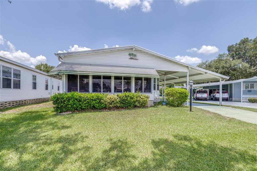 A single-story manufactured home with a screened-in front porch and an attached carport — 6235 KNOTTY PINE DRIVE SE, WINTER HAVEN, FL