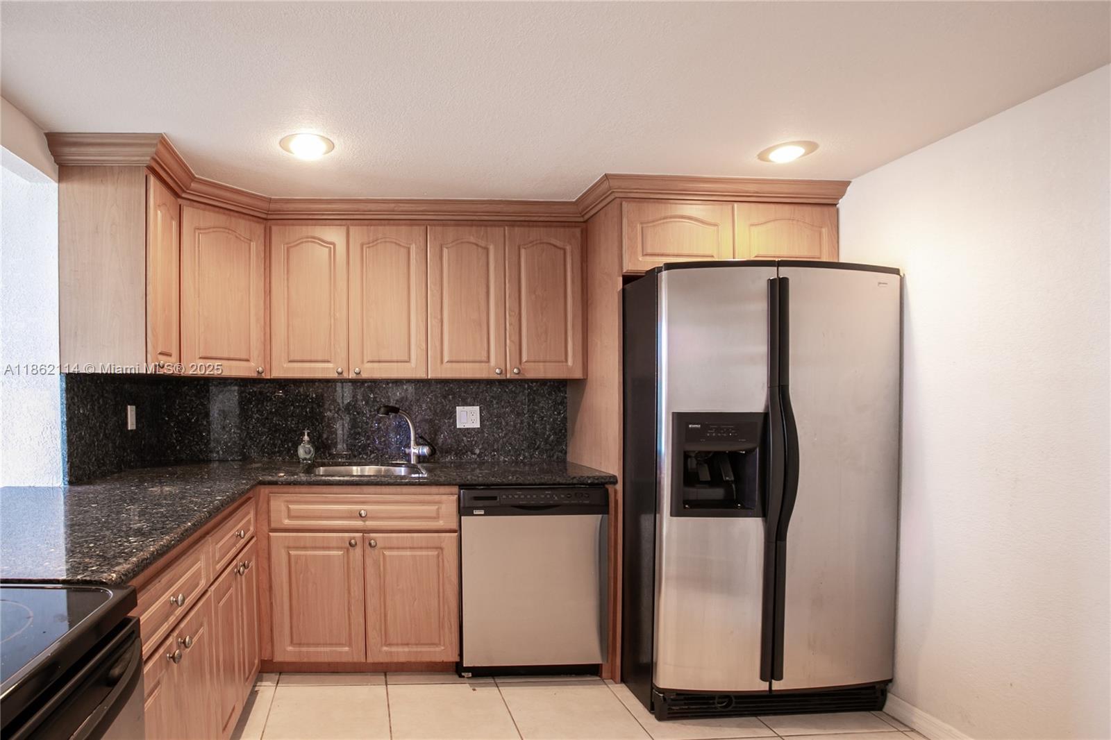 A kitchen features light wood cabinets, dark granite countertops, and stainless steel appliances — 2017 S Ocean Dr # 1008, Hallandale Beach FL 33009, HALLANDALE BEACH, FL