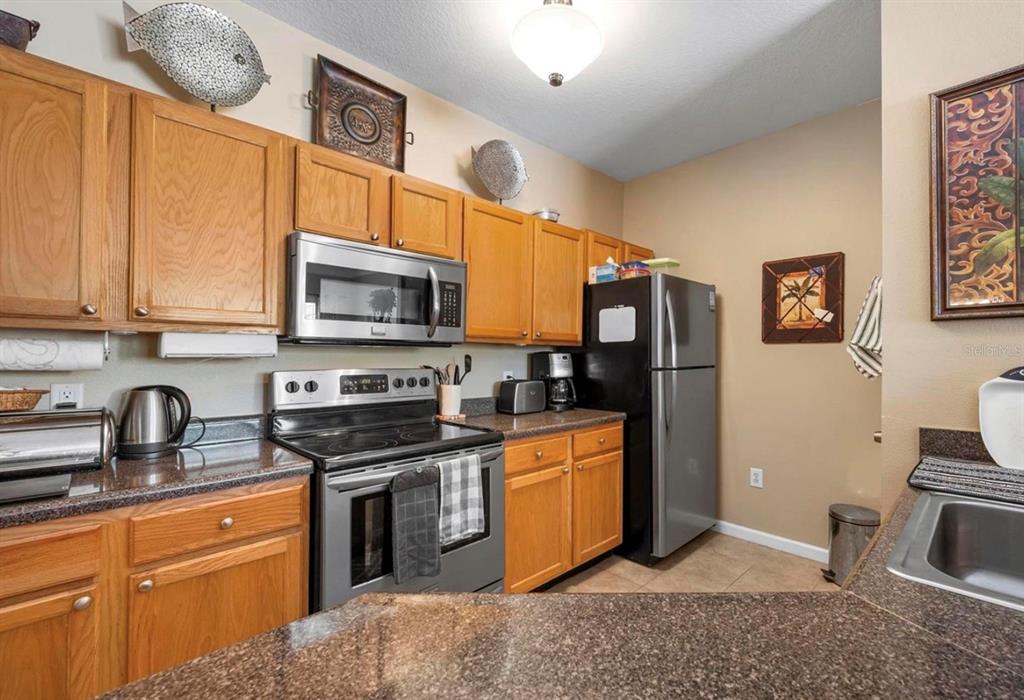 A kitchen features oak cabinets, granite countertops, and stainless steel appliances — 4802 51ST STREET W UNIT 1908, BRADENTON, FL