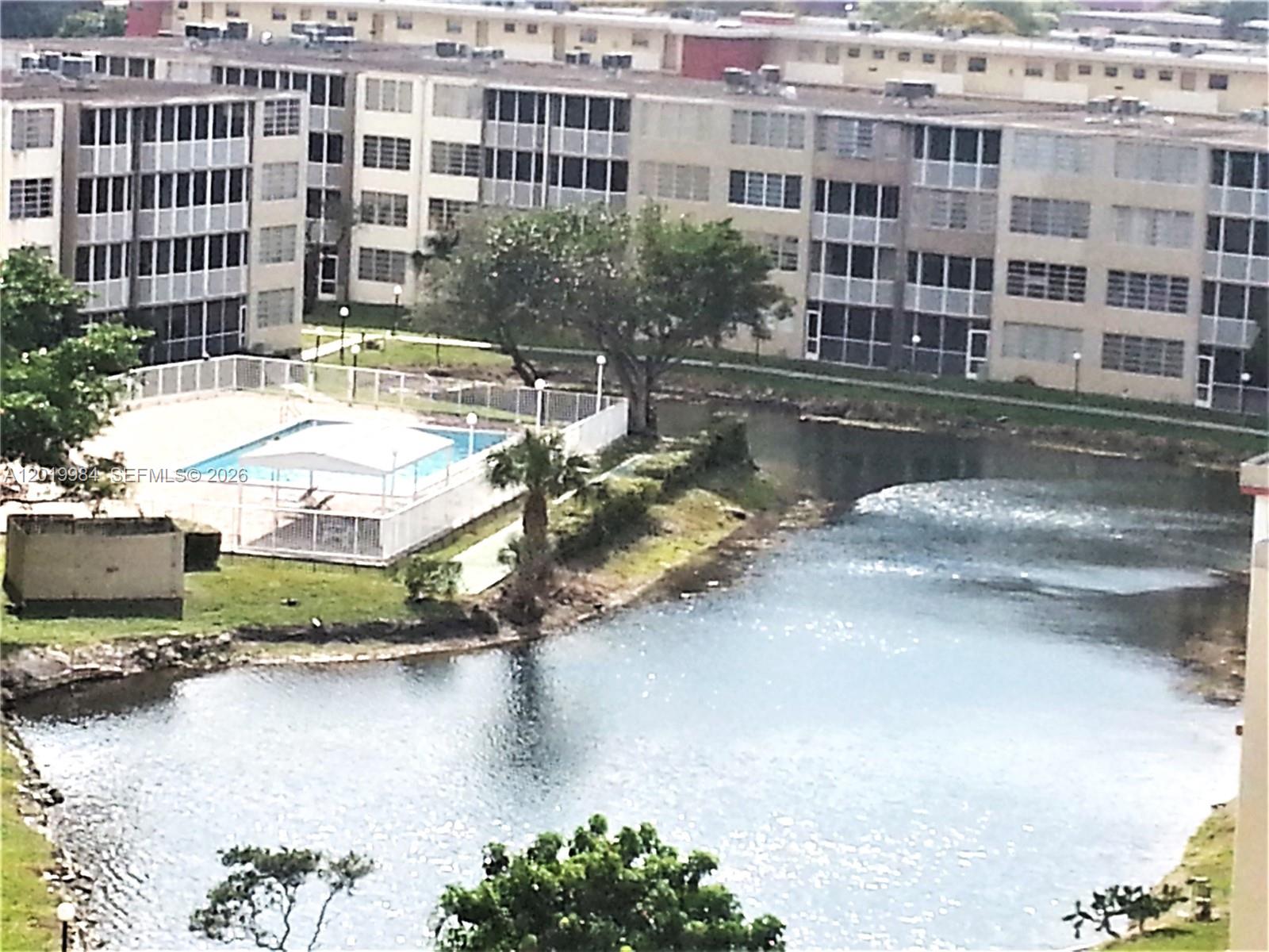 An aerial view shows a swimming pool and a pond next to a large apartment building — 1770 NE 191st St # 1, Miami FL 33179, MIAMI, FL