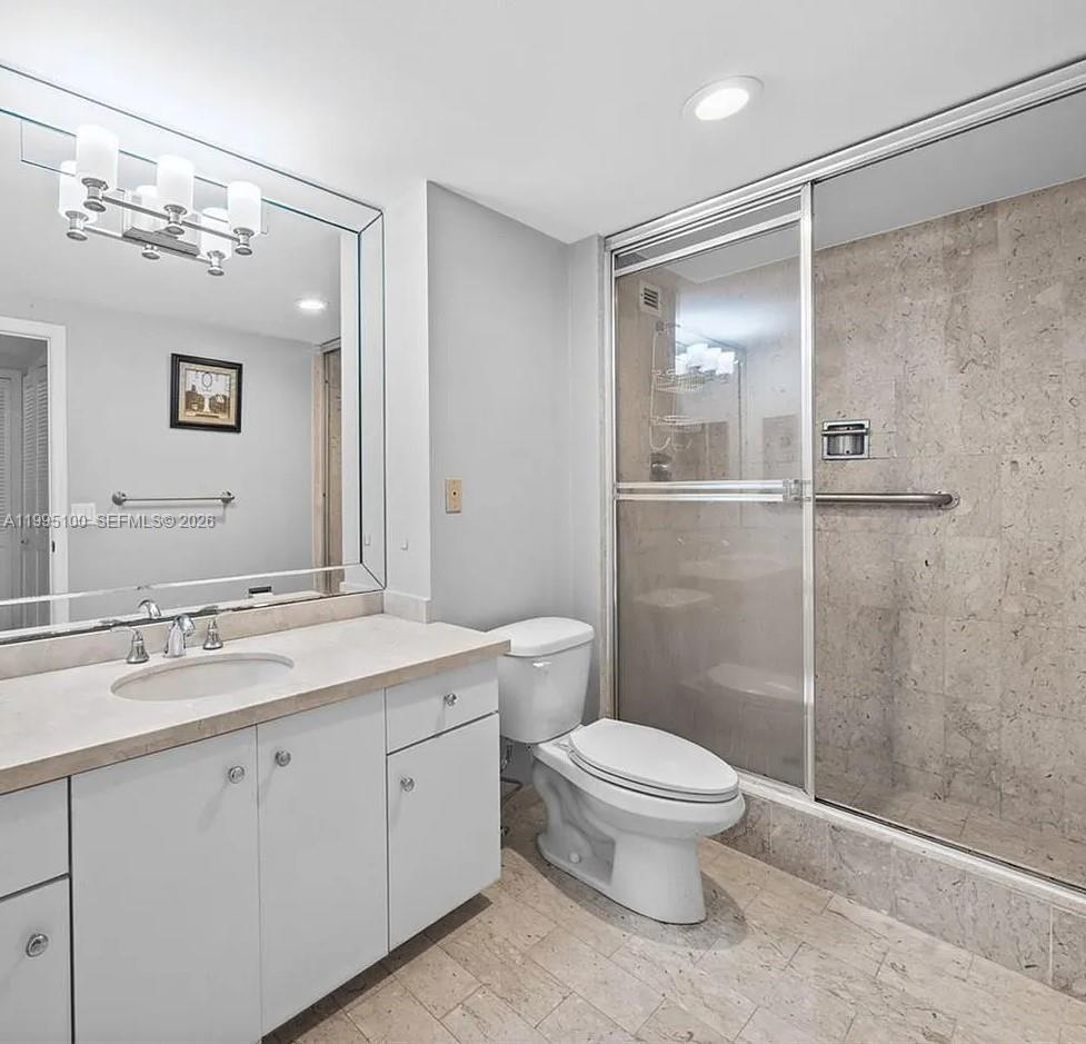 A bathroom features a vanity with a mirror, a toilet, and a glass-enclosed shower — 1800 NE 114th St # 401, Miami FL 33181, MIAMI, FL