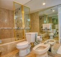 A bathroom features a glass-enclosed shower, a toilet, and a bidet with beige marble walls — 1800 NE 114th St # 401, Miami FL 33181, MIAMI, FL