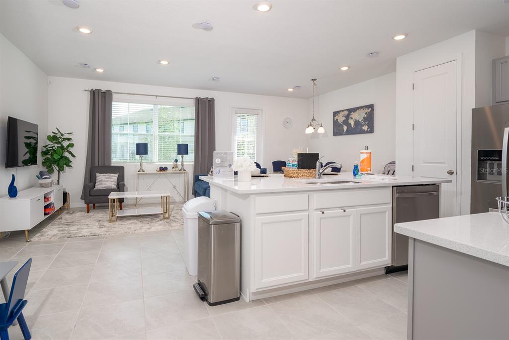 An open-concept kitchen with a white island and stainless steel appliances overlooks a living area — 1029 PLANTATION LANE, DAVENPORT, FL