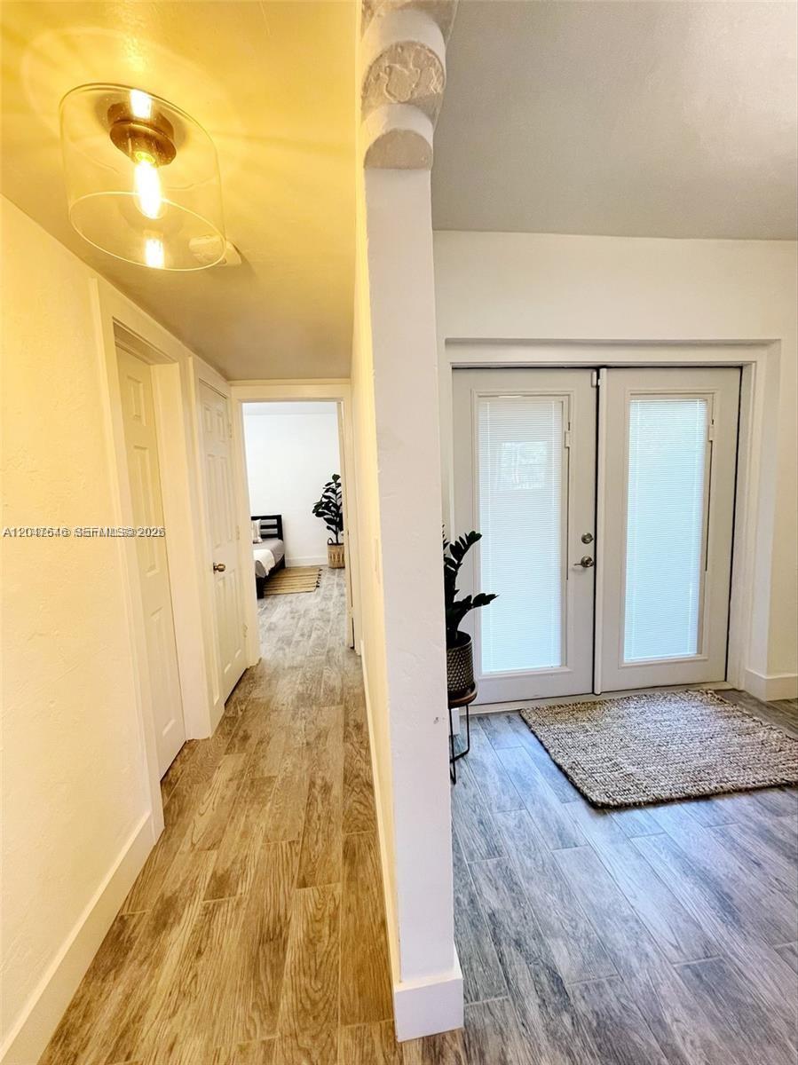 A hallway with wood-look tile flooring leads to a bedroom past a glass-paned double door — 1040 Lenox Ave # 1040, Miami Beach FL 33139, MIAMI BEACH, FL