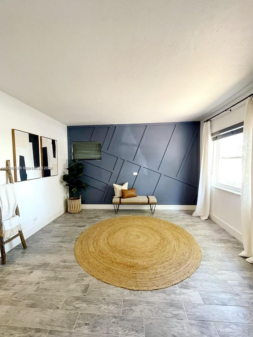 A room features a blue accent wall with geometric molding, a round rug, and tile flooring — 1040 Lenox Ave # 1040, Miami Beach FL 33139, MIAMI BEACH, FL