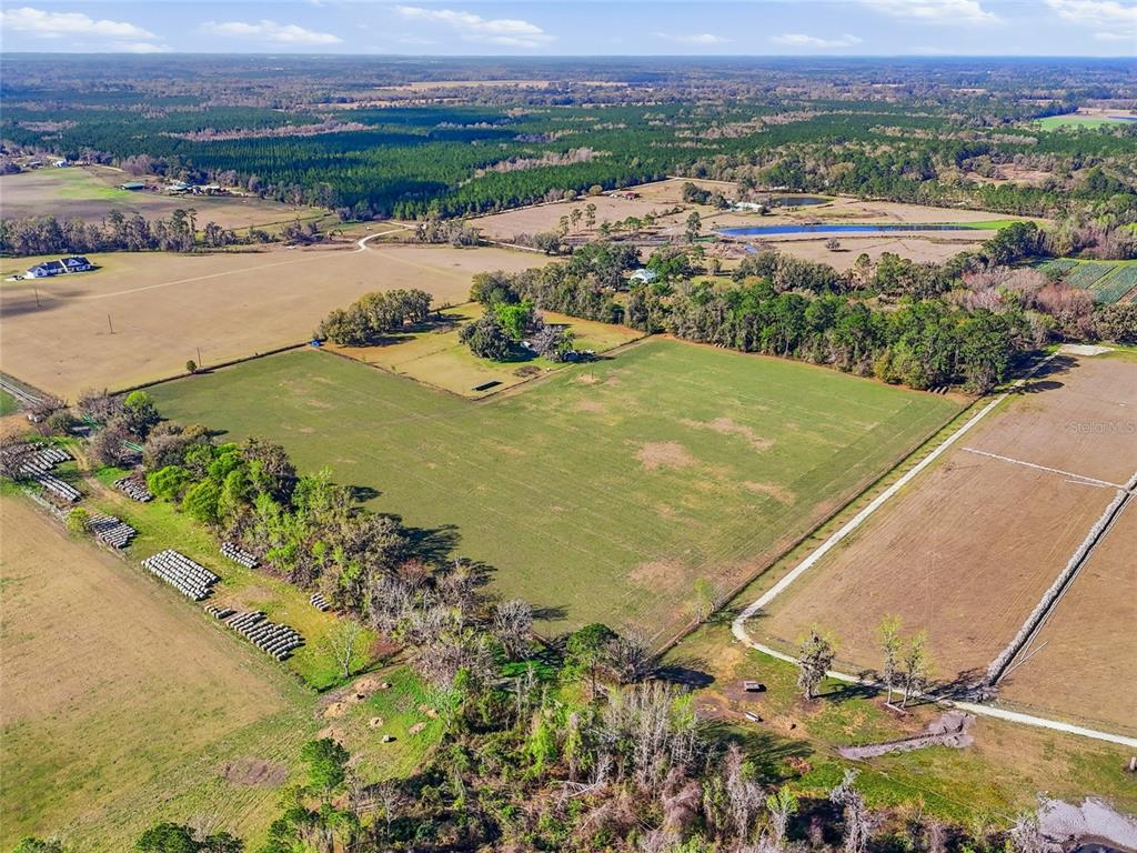 An aerial view shows a large, open pasture surrounded by trees and rural farmland — TBD NW COUNTY RD 239, ALACHUA, FL