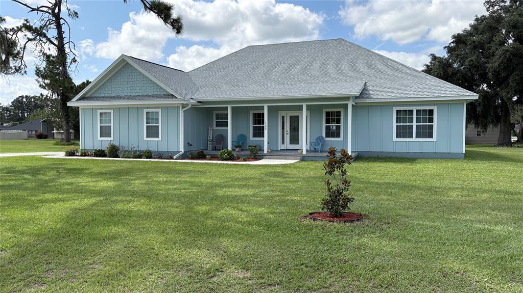 A light blue single-story house with a covered front porch and a large grassy yard — 122 SW SCOTT PLACE, LAKE CITY, FL