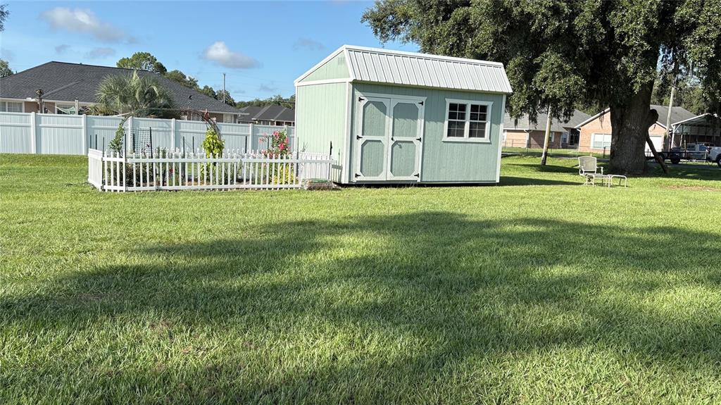 A light green shed with a white roof sits in a large, grassy backyard — 122 SW SCOTT PLACE, LAKE CITY, FL