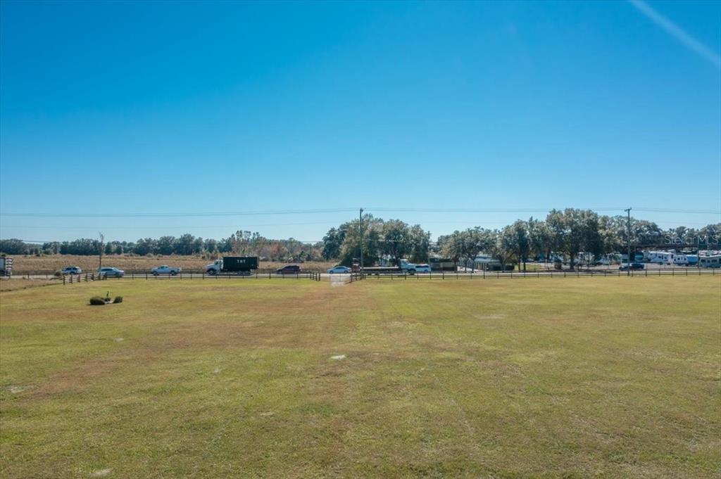 A large, flat, grassy field sits in front of a road with passing vehicles — 31935 COUNTY ROAD 52, SAN ANTONIO, FL