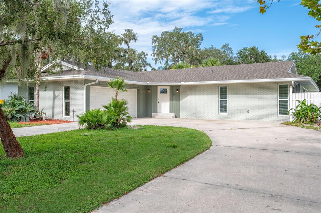 A single-story brick house with a white front door, attached garage, and concrete driveway — 407 PRINCESS PLACE, LAKELAND, FL