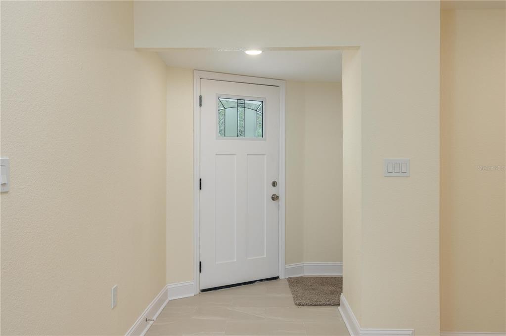 A white front door with a glass insert opens into a tiled entryway — 407 PRINCESS PLACE, LAKELAND, FL