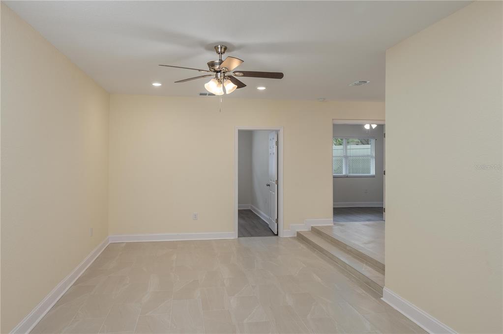 A room with light-colored tile flooring, a ceiling fan, and a step-up to another area — 407 PRINCESS PLACE, LAKELAND, FL