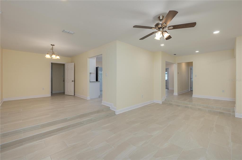 An open-concept living area features light-colored tile flooring, pale yellow walls, and two stepped levels — 407 PRINCESS PLACE, LAKELAND, FL