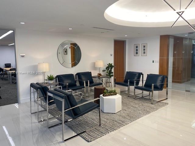 A modern office waiting area features dark leather armchairs, a geometric coffee table, and a mirror — 2 S Biscayne Blvd # 3200, Miami FL 33131, MIAMI, FL