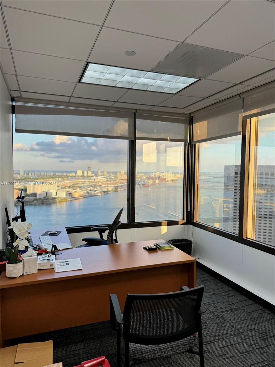 An office with a wooden desk, black chairs, and floor-to-ceiling windows overlooking a harbor — 2 S Biscayne Blvd # 3200, Miami FL 33131, MIAMI, FL