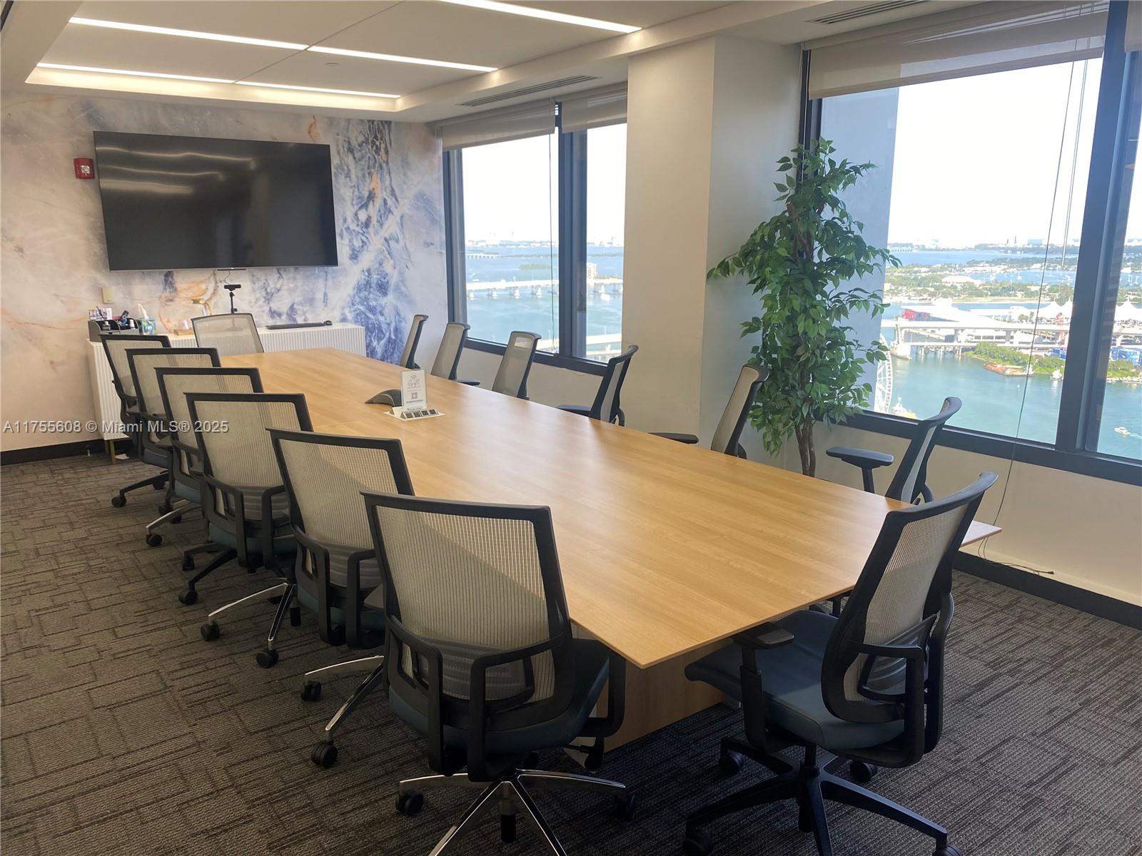 A conference room features a long wooden table, mesh chairs, and a view of the bay — 2 S Biscayne Blvd # 3200, Miami FL 33131, MIAMI, FL