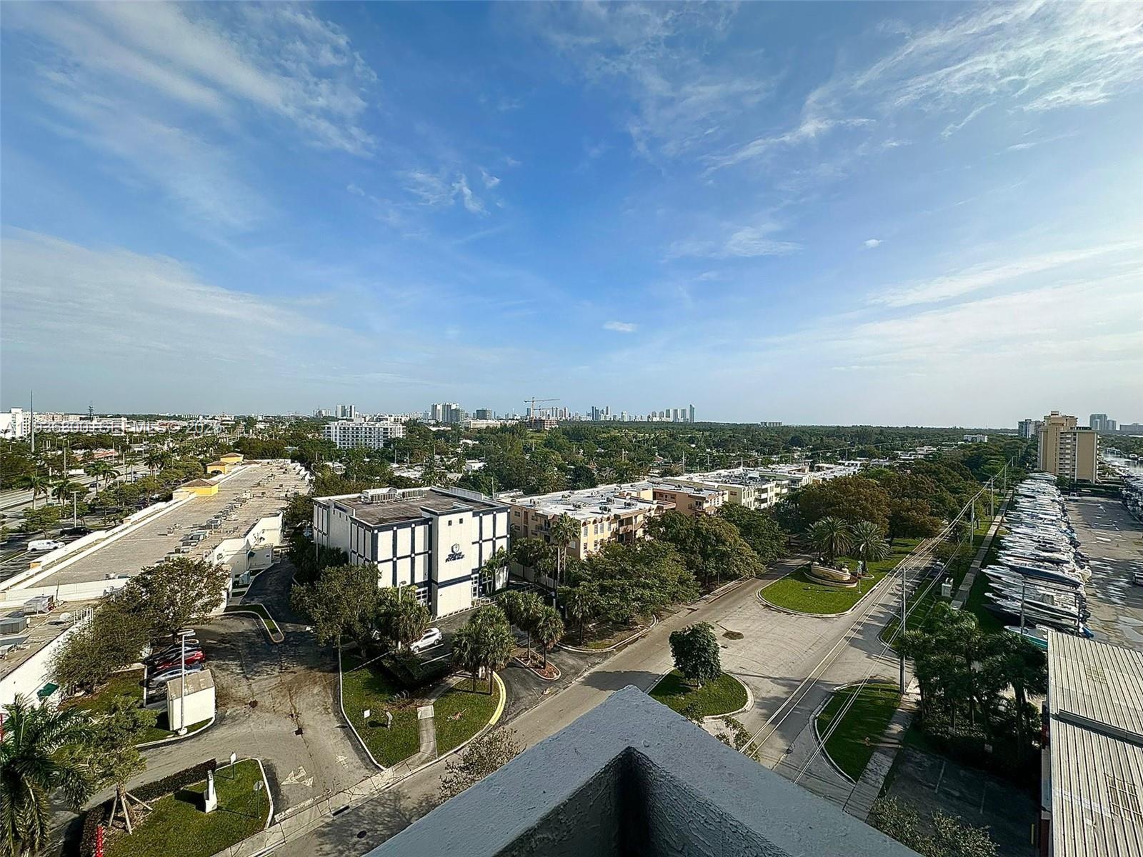 An elevated view of a suburban landscape featuring a marina, parking lots, and distant buildings — 13499 Biscayne Blvd # 1013, North Miami FL 33181, NORTH MIAMI, FL