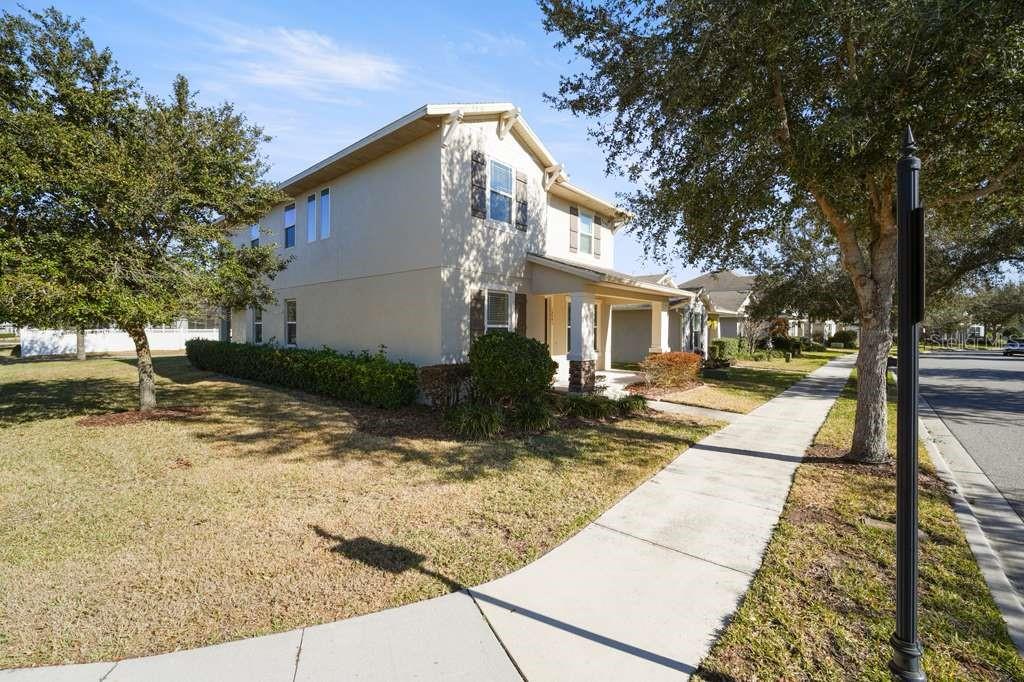 A two-story beige house with a front porch and a sidewalk in the foreground — 15043 PIGEON PLUM LANE, WINTER GARDEN, FL