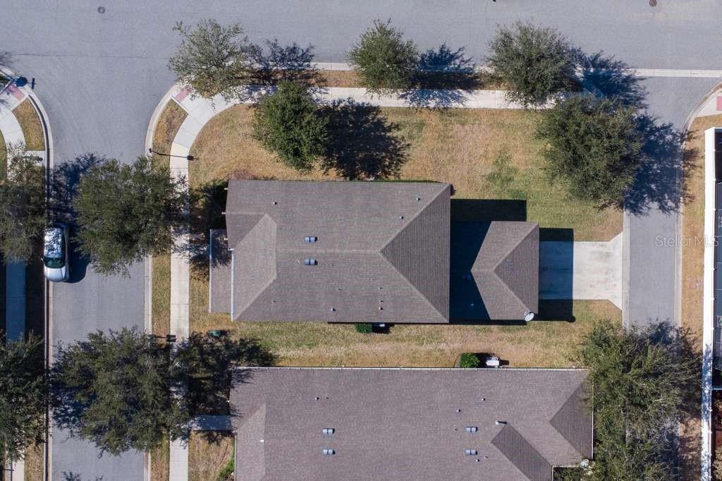 An aerial view shows a single-family home with a gray roof on a corner lot — 15043 PIGEON PLUM LANE, WINTER GARDEN, FL