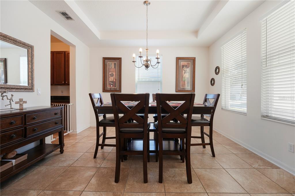 A dining room features a dark wood table and chairs, tile flooring, and a chandelier — 15043 PIGEON PLUM LANE, WINTER GARDEN, FL