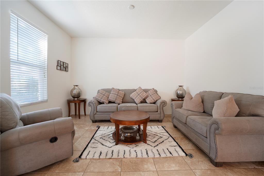 A living room features gray sofas, a round wooden coffee table, and a patterned rug — 15043 PIGEON PLUM LANE, WINTER GARDEN, FL