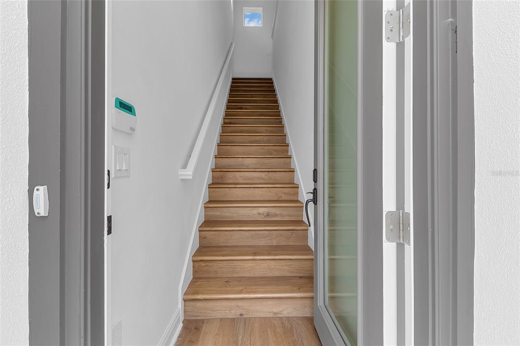A staircase with wood treads leads upward between white walls in a modern entryway — 9687 MACBRIDE DRIVE, ORLANDO, FL