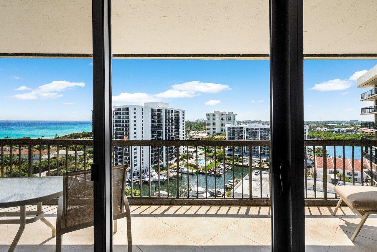 A balcony with tile flooring overlooks a marina, high-rise buildings, and the ocean — 4740 S Ocean Boulevard # 1515, Highland Beach FL 33487, HIGHLAND BEACH, FL