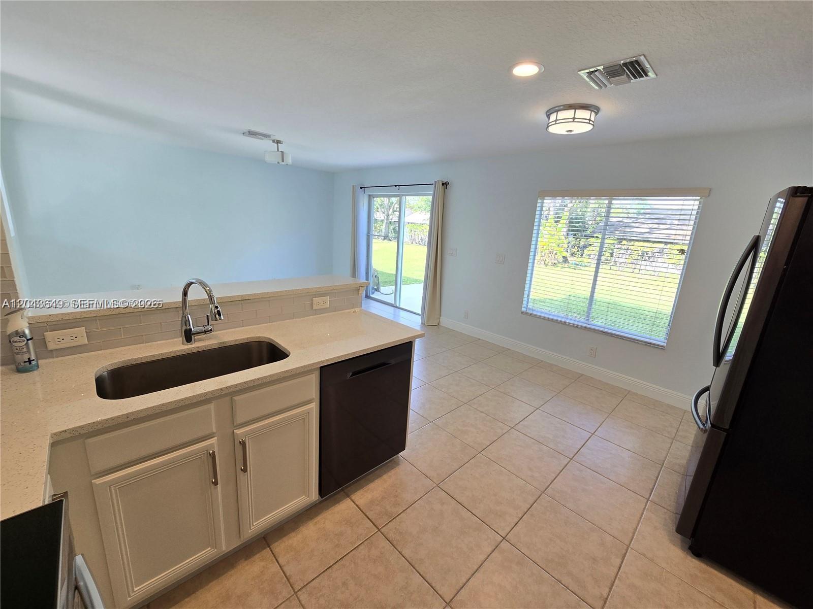 A kitchen with white cabinets, a stainless steel sink, and a view of the backyard — 4670 SE Graham Dr, Stuart FL 34997, STUART, FL
