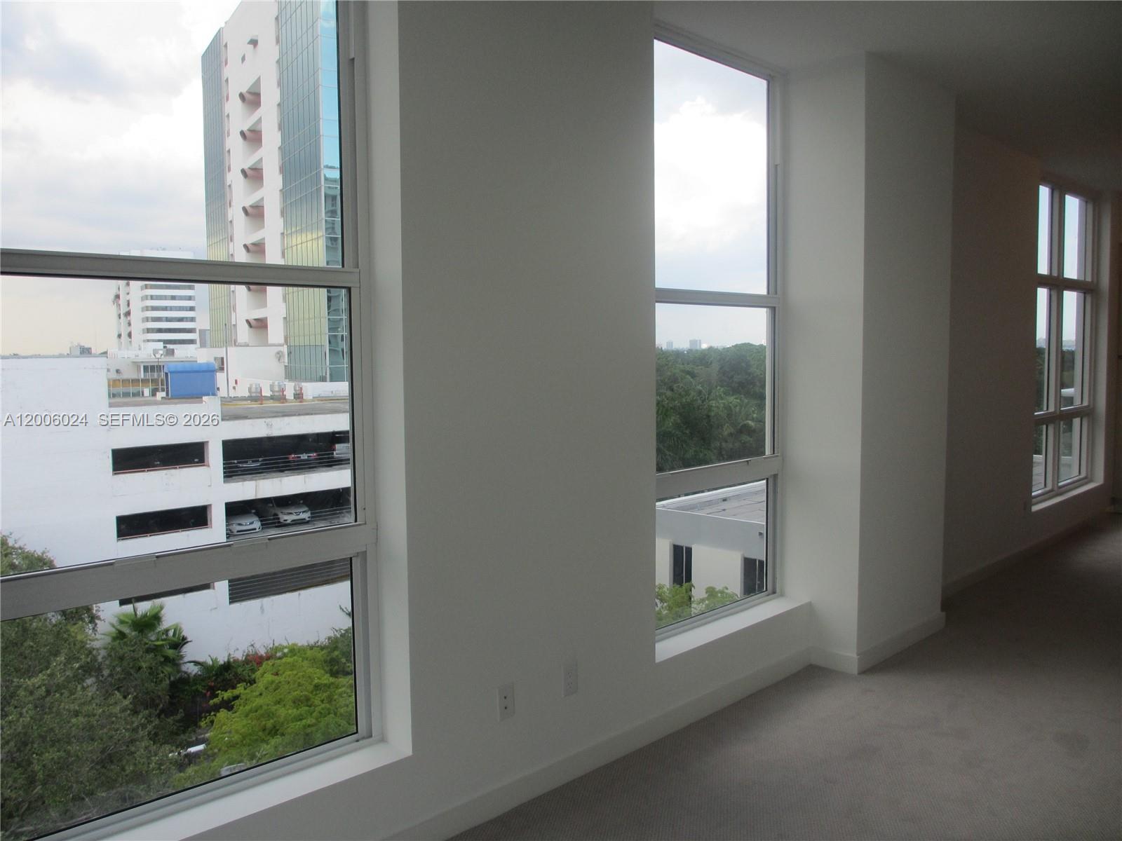 An interior view of a room with carpeted floors and large windows overlooking a city — 4250 Biscayne Blvd # 610, Miami FL 33137, MIAMI, FL