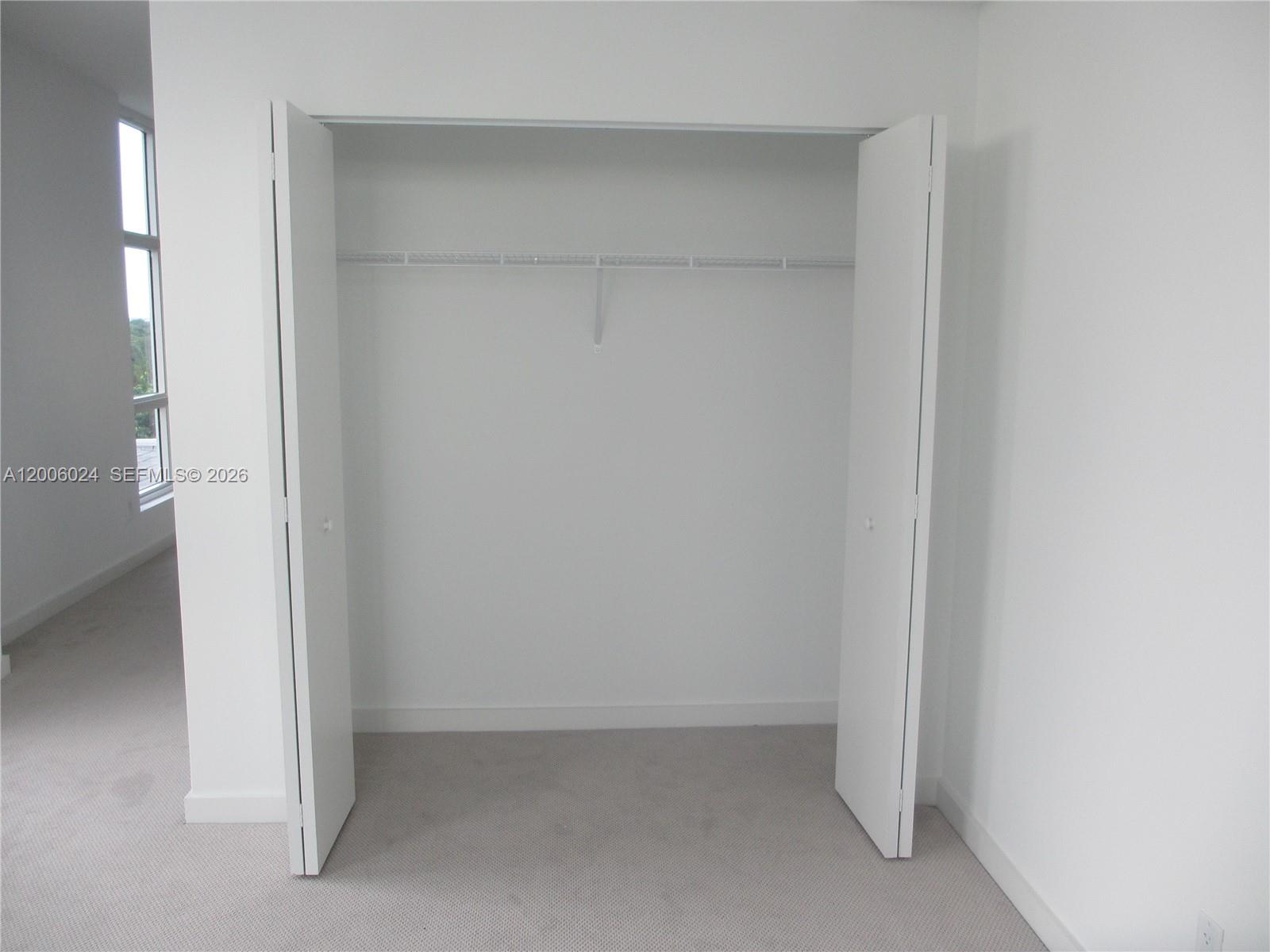 A white bedroom closet with a wire shelf and folding doors sits on carpeted flooring — 4250 Biscayne Blvd # 610, Miami FL 33137, MIAMI, FL