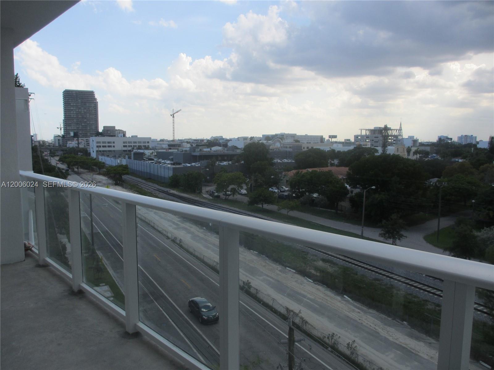 A balcony view overlooks a multi-lane road, railroad tracks, and a distant city skyline — 4250 Biscayne Blvd # 610, Miami FL 33137, MIAMI, FL