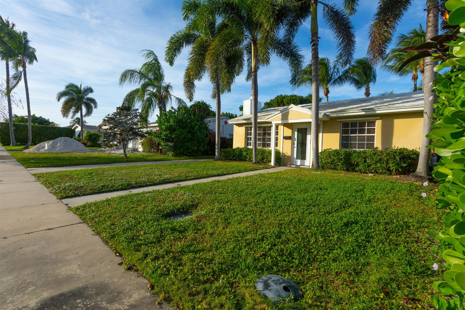 A yellow single-story house with a white door and palm trees in the front yard — 245 Cortez Road, West Palm Beach FL 33405, WEST PALM BEACH, FL