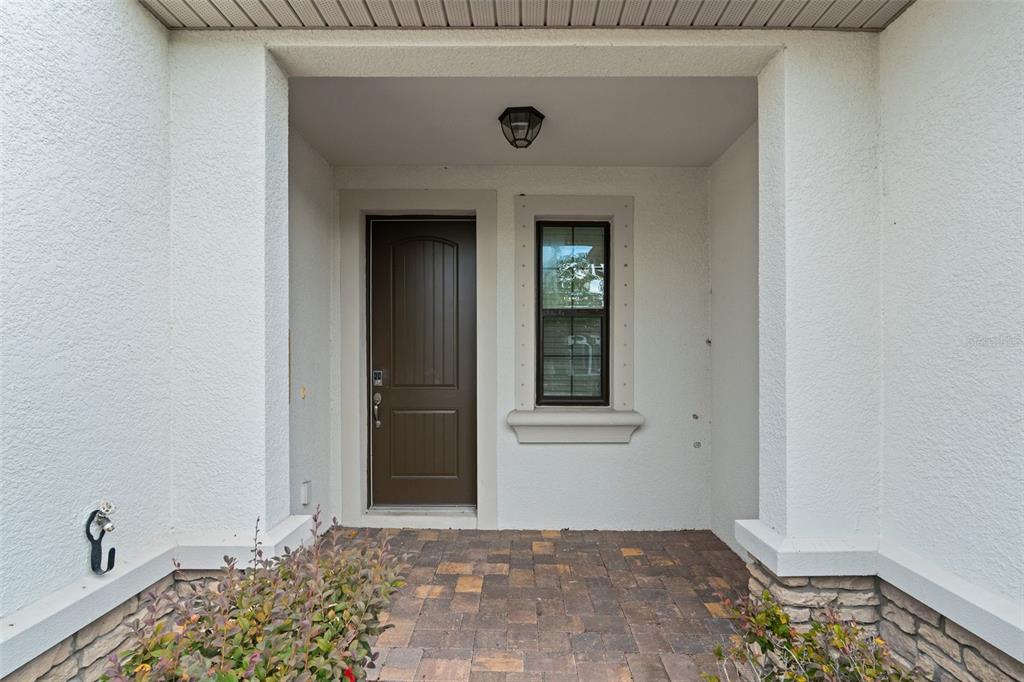 A front entryway features a brown door, a single window, and a paver porch — 5248 BLOSSOM COVE, BRADENTON, FL