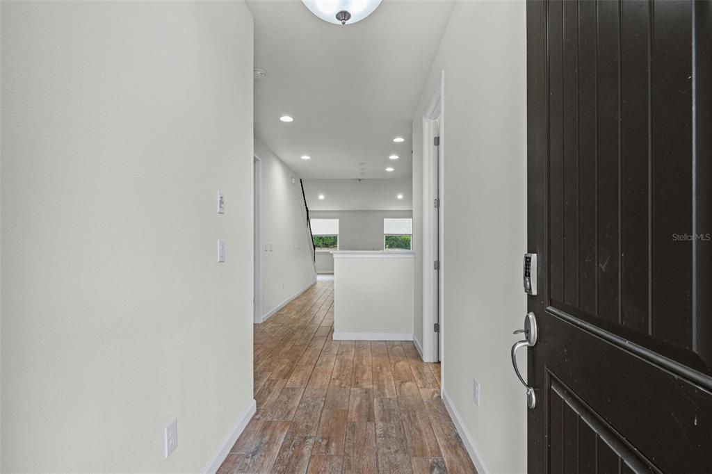 A view from an entryway looking down a hallway with wood-look tile flooring — 5248 BLOSSOM COVE, BRADENTON, FL