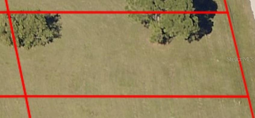 An aerial view shows a grassy, vacant lot outlined in red with two clusters of trees — 4142 NW 40TH AVENUE, CAPE CORAL, FL