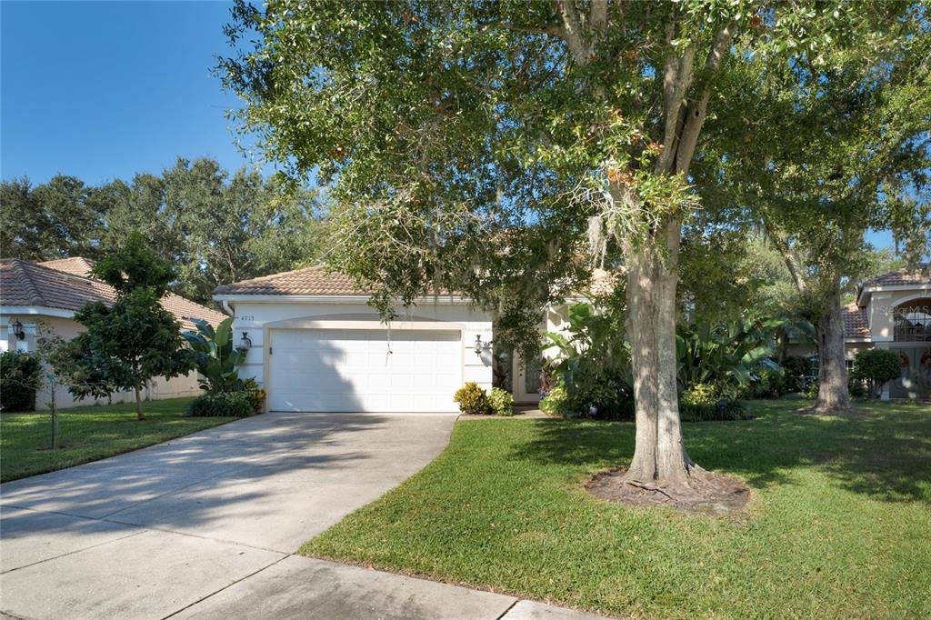A single-story house with a white garage, a concrete driveway, and large trees in front — 4713 WINDSOR AVENUE, ORLANDO, FL